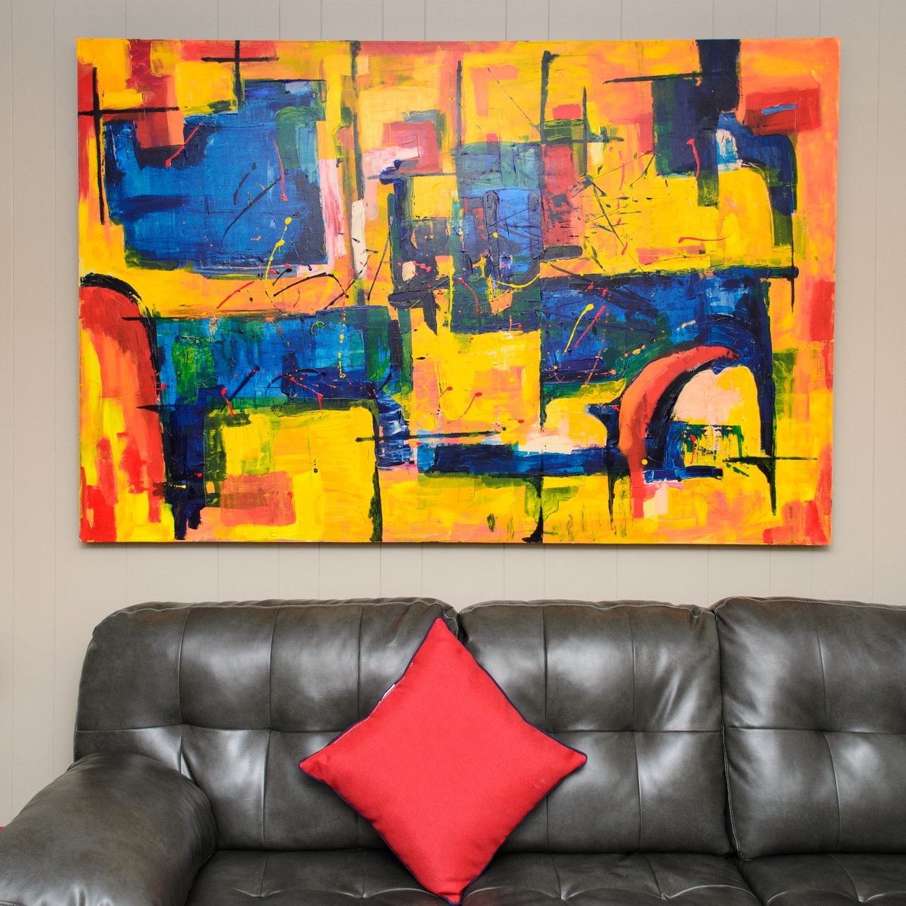 Abstract painting with vibrant primary colors above a leather sofa